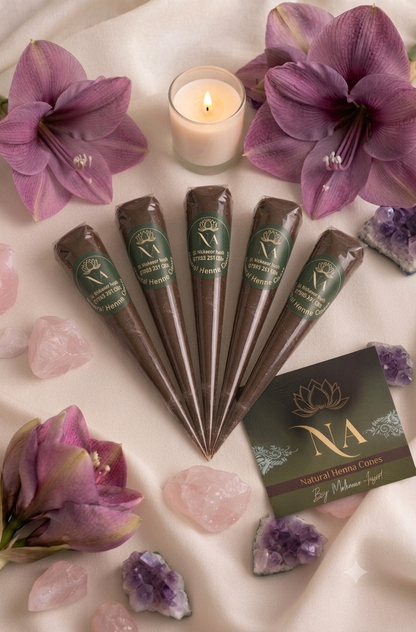 Five cone-shaped natural hair extensions in dark brown are arranged in a fan shape on a draped cream fabric, surrounded by purple amaryllis, pink and purple crystals, a lit candle, and a branded NA Natural Hair Extensions card.